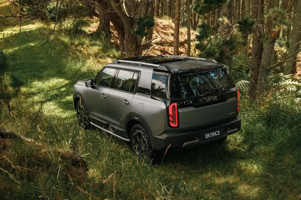 Rear three quarter view of a dark grey BAIC B30 SUV parked in a NZ forest