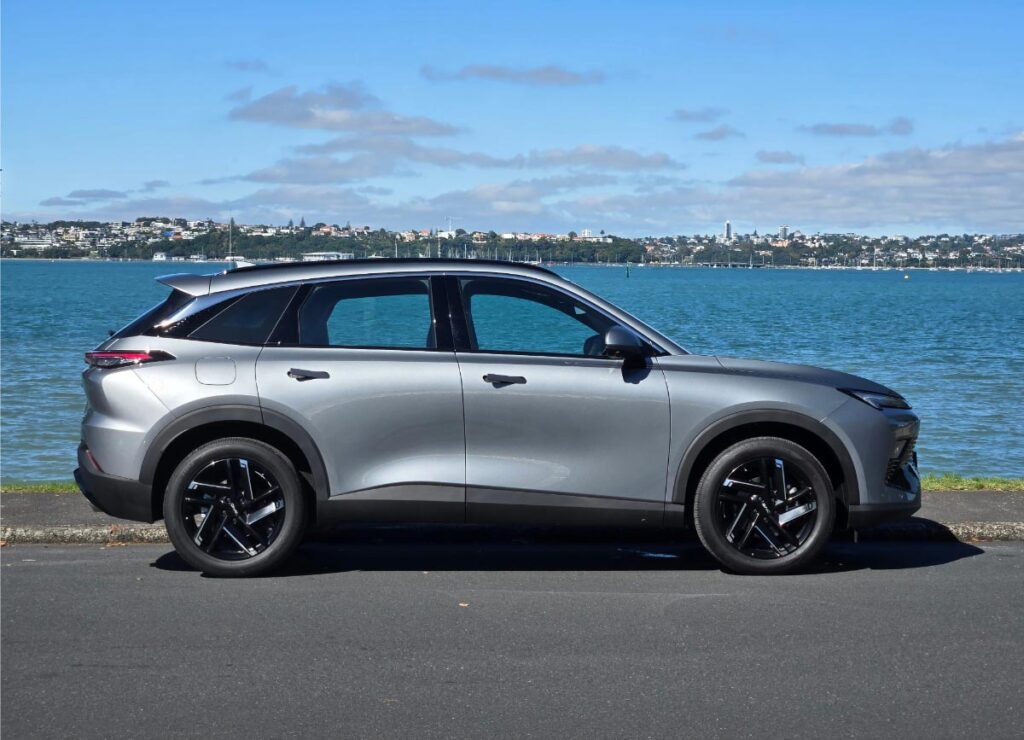 Side view of a silver BAIC X55 crossover SUV parked in front of a harbour