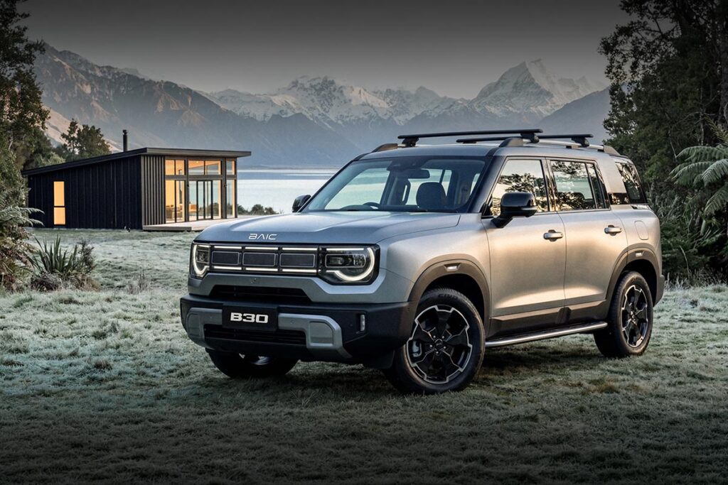 Front three quarter view of a silver BAIC B30 SUV parked by a lake cabin amongst  snow-covered mountains