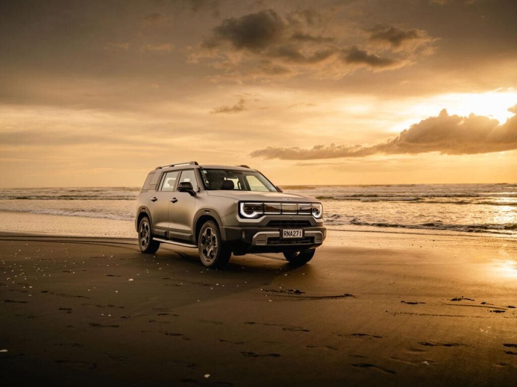 Front three quarter view of a silver BAIC B30 SUV driving on a beach at sunrise