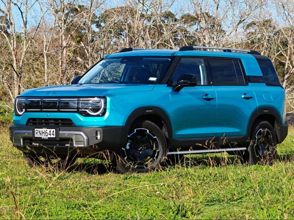Front three quarter view of a blue BAIC B30 SUV Premium Adventure Hybrid AWD parked in a field
