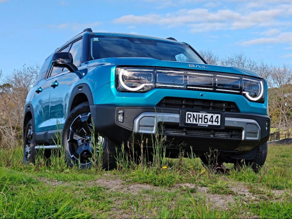 Front view of a blue BAIC B30 SUV Premium Adventure Hybrid AWD parked in a field