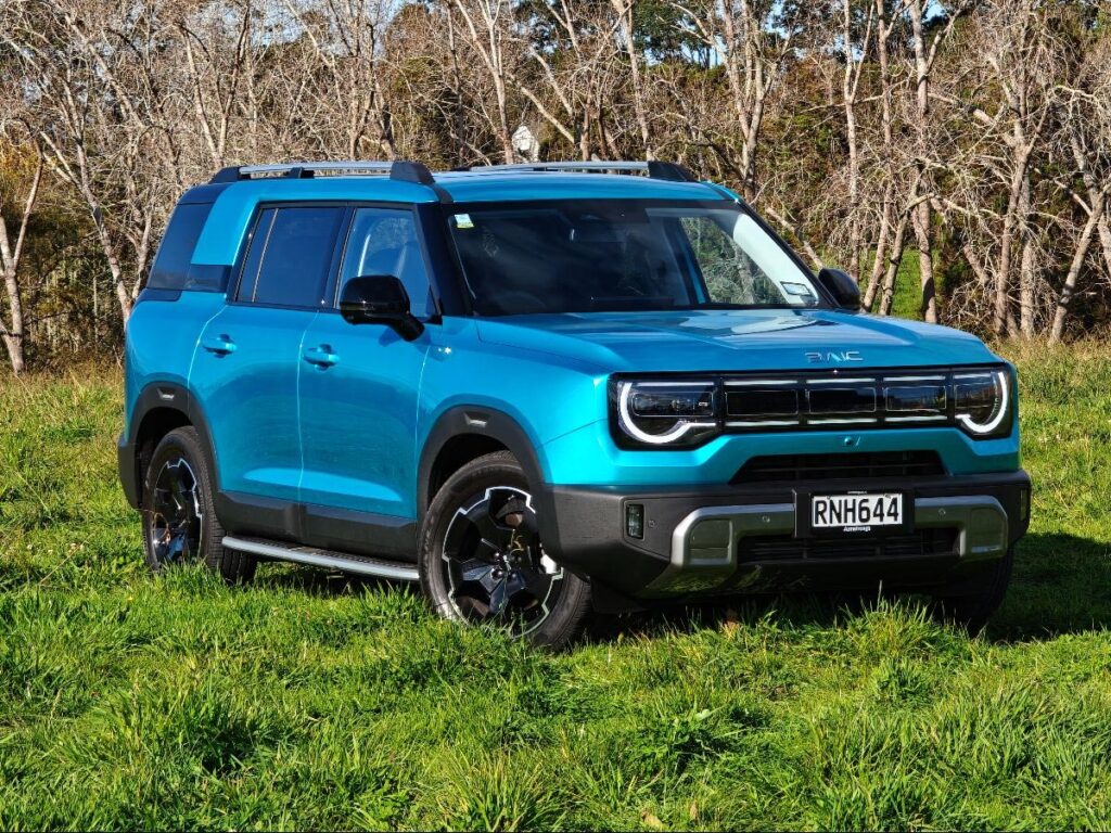 Front three quarter view of a blue BAIC B30 SUV Premium Adventure Hybrid AWD parked in a field